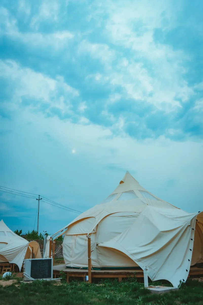 Witte glampingtenten onder een blauwe lucht