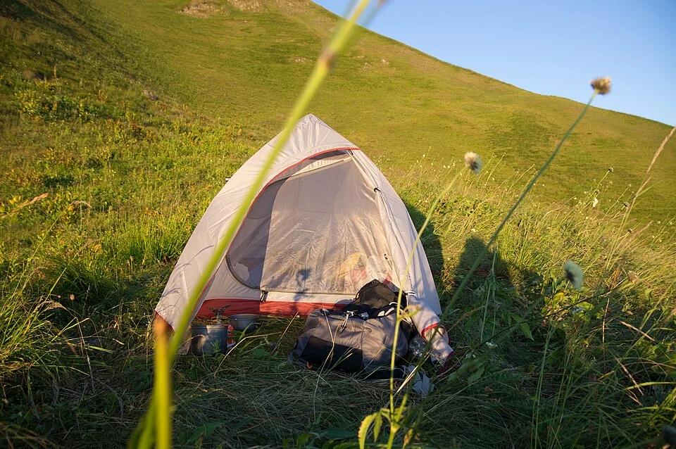 Een kleine tent in het groene berglandschap van de Kaukasus
