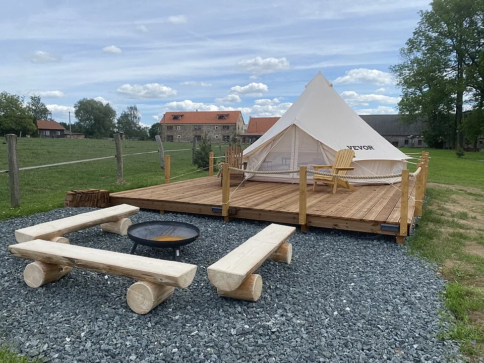 Een glampingtent met terras op een ruime groene plek